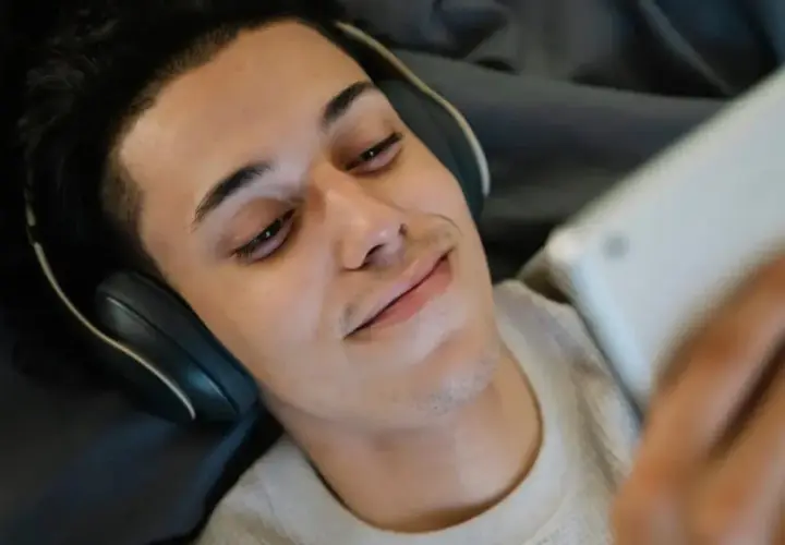 Giovane con cuffie e tablet, forse in un momento di solitudine, tra autoerotismo e depressione.