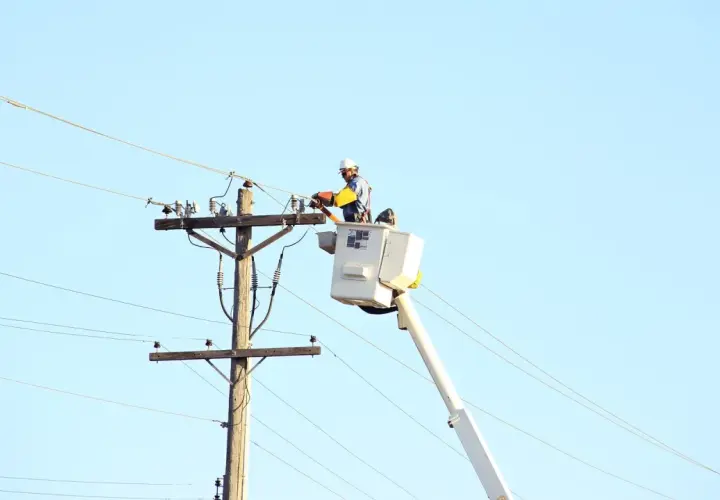 Elektryk wysokich napięć w podnośniku pracuje przy linii energetycznej.