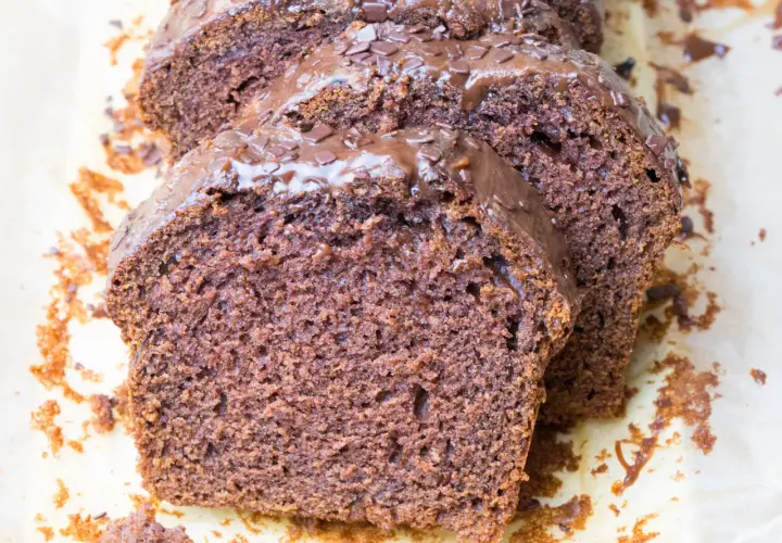 Pokrojone ciasto czekoladowe z polewą i posypką na papierze do pieczenia.