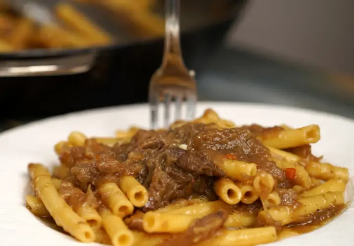 Un piatto invitante di ziti alla genovese, con la pasta condita da un ricco ragù di carne e cipolle.
