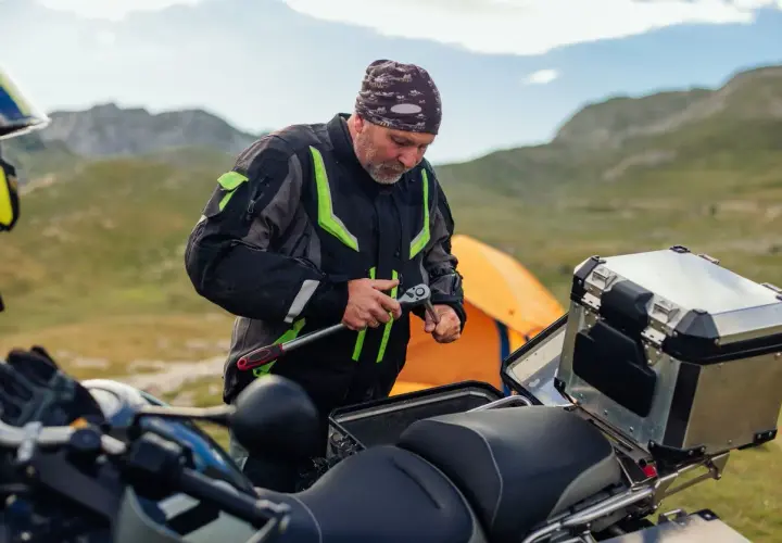 Motociclista repara su moto en la montaña, quizás para evitar que se ahoga la moto.