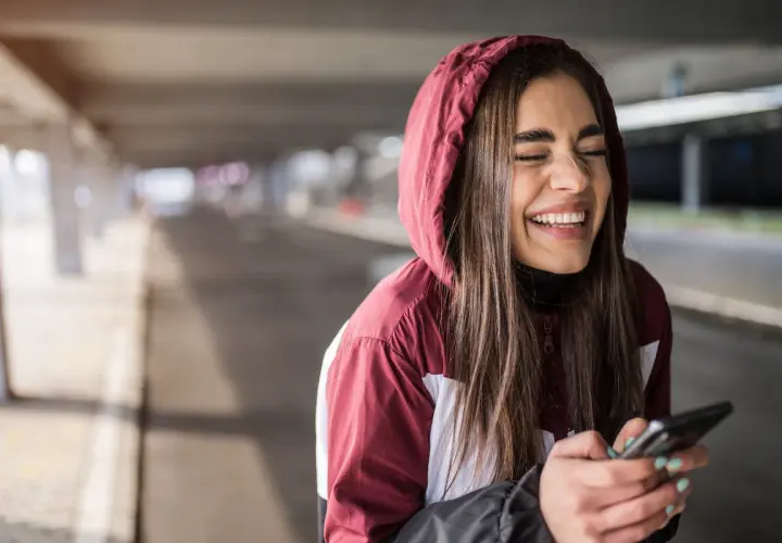 Ragazza ride a crepapelle guardando il telefono, un momento che fa capire che significa lmao.