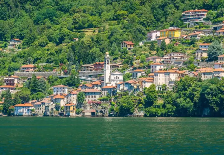 Ein malerisches Dorf am Nesso Comer See, mit traditionellen Häusern, die sich an den grünen Hang schmiegen.