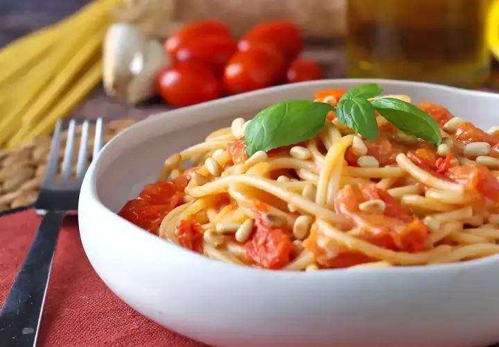 Spaghetti con pomodorini, pinoli e basilico, uno dei tanti sughi per pasta che invitano a gustare la semplicità.