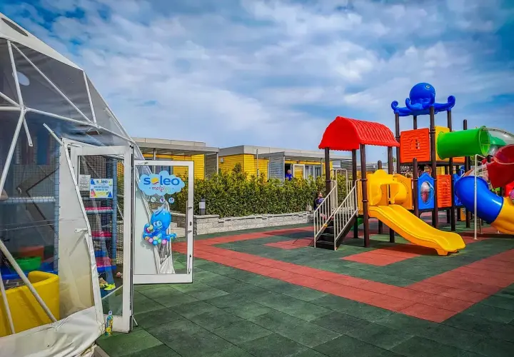 Kolorowy plac zabaw z ośmiornicą i zjeżdżalniami, idealne rewa atrakcje dla dzieci. Obok namiot z atrakcjami dla najmłodszych.