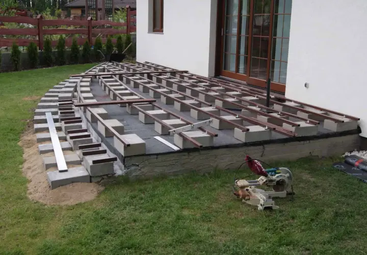 Budowa tarasu kompozytowego: widać betonowe bloczki i legary, które wyznaczają rozstaw co ile legary pod taras kompozytowy.