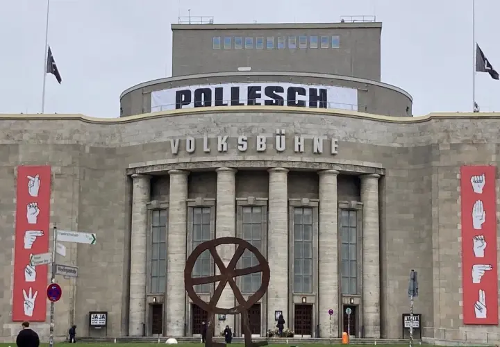 Volksbühne Berlin mit Banner "POLLENSCH". Annegret Hahn könnte hier eine Aufführung besuchen. Rote Banner mit Gebärdensprache.