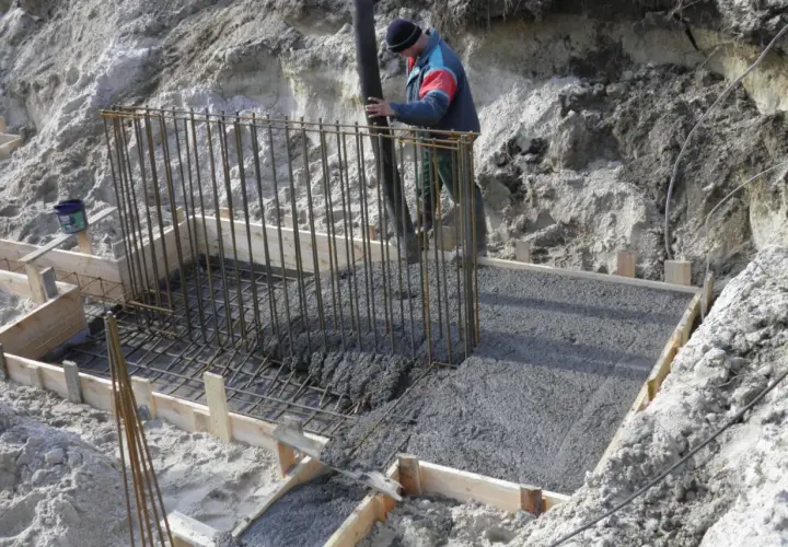 Wylany beton w szalunku, pracownik wylewa masę, mimo że czuć już przymrozek.