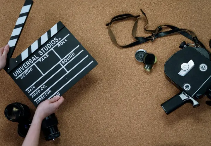 Kamera filmowa, klaps z napisem "Universal Studios" i obiektywy. To wszystko, co potrzebne do stworzenia opisu filmu po angielsku.