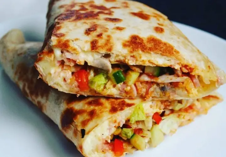 Złocista tortilla z jajkiem, serem i szynką, wypełniona warzywami, usmażona na patelni. Pyszne danie na szybki posiłek.