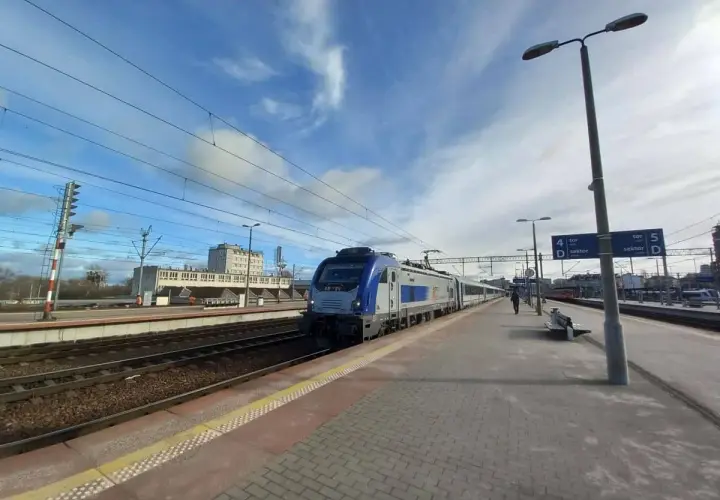 Pociąg na stacji, idealny środek transportu, by dowiedzieć się, jak dostać się do morza. Słońce i chmury na niebie.