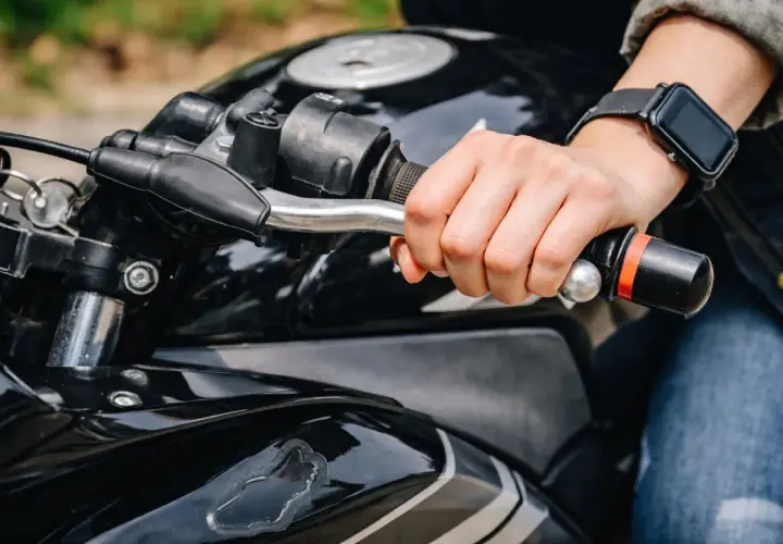 Mano sujetando el manillar de una moto negra, lista para arrancar. Aprender a no picar embrague es clave para una conducción suave.