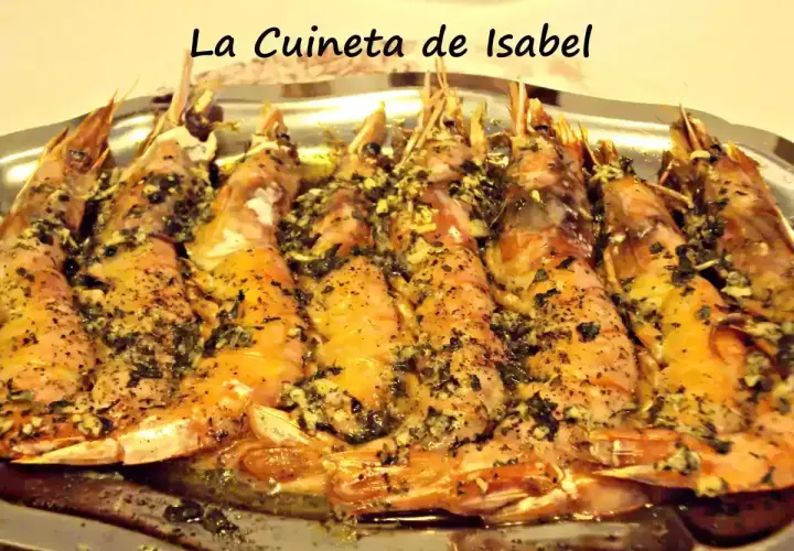 Langostinos al horno, jugosos y dorados, con hierbas y ajo, servidos en una bandeja metálica. ¡Un manjar de La Cuineta de Isabel!