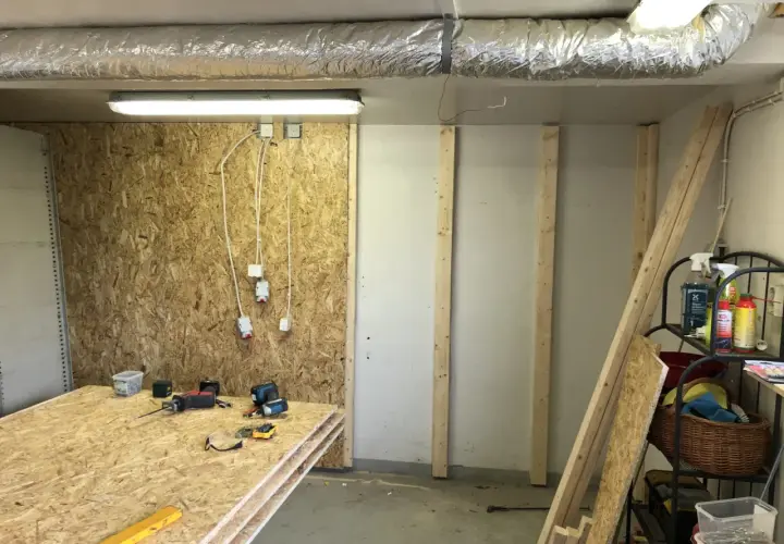 Här ligger skivor av OSB redo att måla. Verktyg och byggmaterial finns på plats för projektet.
