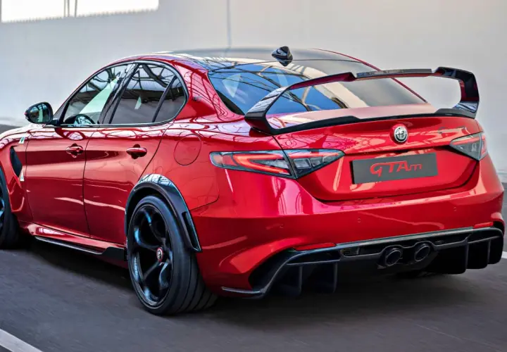 Czerwone Alfa Romeo Giulia GTAm z masywnym spoilerem i dyfuzorem, gotowe do wyścigu.