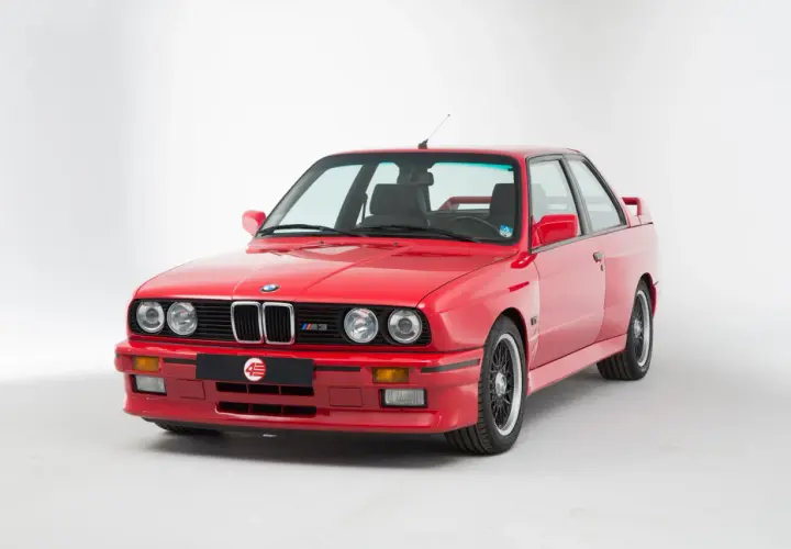 Klasyczne czerwone bmw e30 coupe z czarnymi felgami i emblematem M3. Ikona motoryzacji.