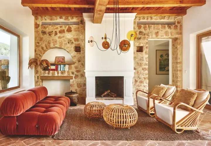 Gemütliches Wohnzimmer im Boho-Stil mit Terrakotta-Boden, Steinwand, Korbmöbeln und einem roten Samtsofa. Die boho bedeutung zeigt sich in der entspannten Atmosphäre.