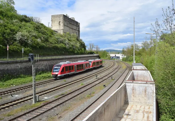 Roter Zug fährt auf Gleisen an einer Burgruine vorbei. br 640.