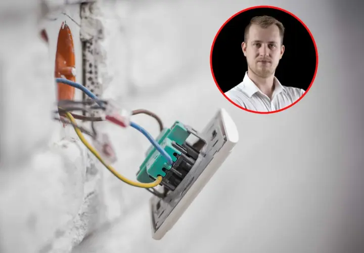 Prąd budowlany w ścianie, instalacja elektryczna w trakcie prac. W tle mężczyzna w białej koszuli.