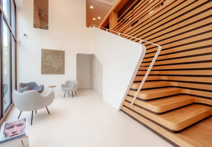 Nowoczesne wnętrze z białymi schodami i drewnianą ścianą. Fotograf architektury uchwycił minimalistyczny design i grę światła.
