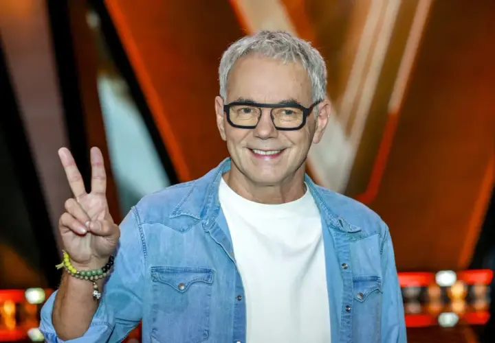 Robert Janowski, syn księdza, w dżinsowej koszuli i okularach, pokazuje znak pokoju.