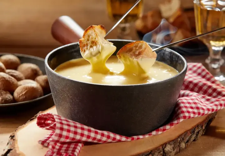 Un délicieux moment de partage autour d'une fondue savoyarde crémeuse, avec du pain croustillant trempé dans le fromage fondu.