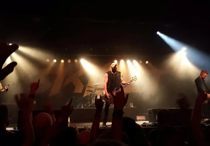 Koncert jednego z najsłynniejszych zespołów rockowych. Wokalista z basem na scenie, tłum szaleje.