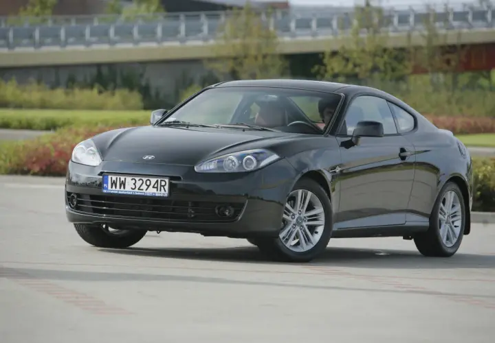 Czarny Hyundai Coupe 2.7 V6 z przyciemnionymi szybami i sportowymi felgami, zaparkowany na zewnątrz.
