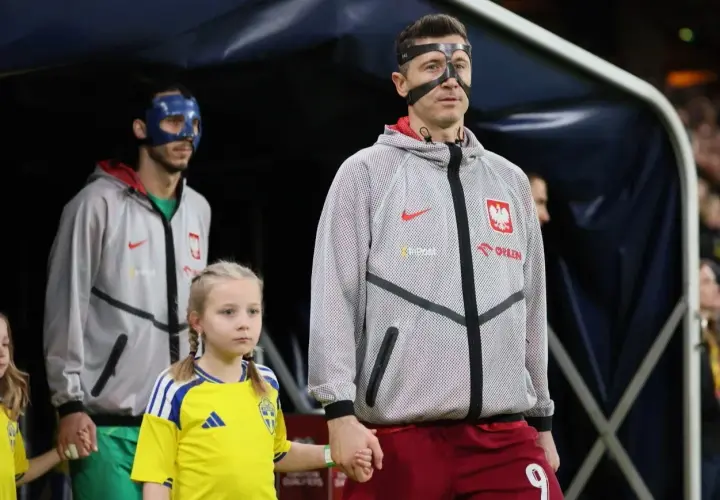 Polscy piłkarze, w tym Robert Lewandowski, wychodzą na murawę z dziećmi. Jeden z zawodników ma niebieską maskę.