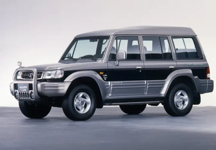 Srebrny Hyundai Galloper V6 LPG, terenowy SUV z lat 90. z czarnymi pasami na drzwiach.