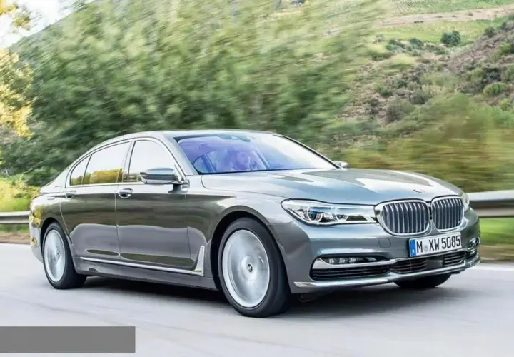 Eleganckie BMW 730d sunie po krętej drodze wśród zieleni.