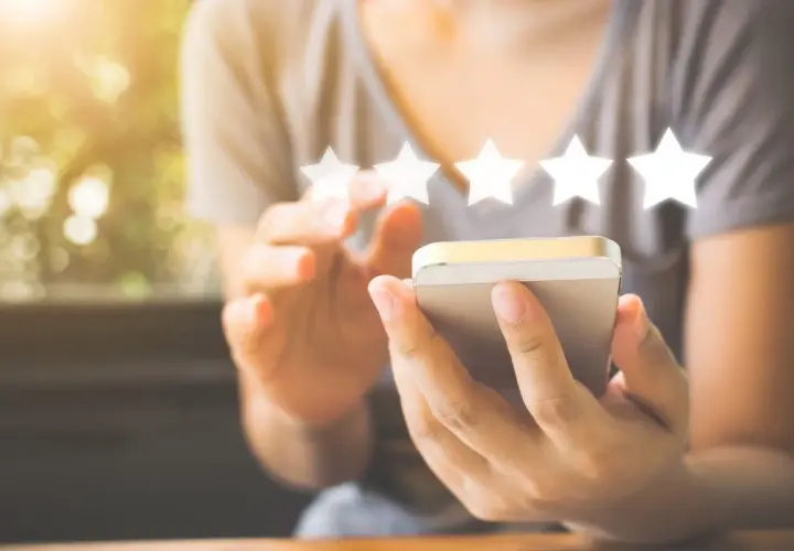 Une personne utilise son smartphone pour laisser un avis 5 étoiles, un élément clé du marketing digitale.