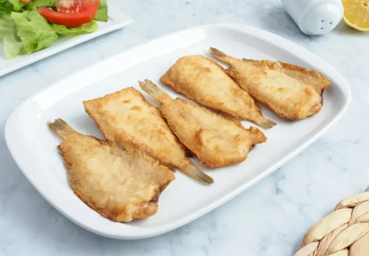 Cinco acedias fritas doradas y crujientes en un plato blanco, listas para disfrutar.