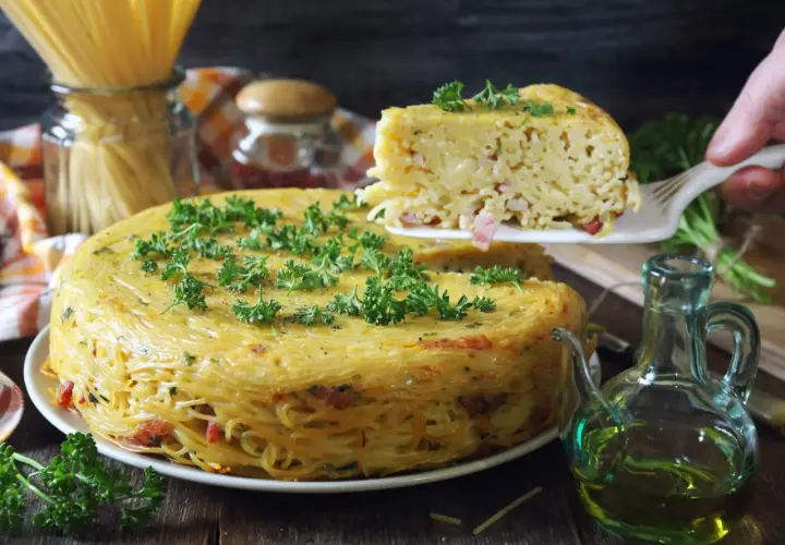 Pyszne spaghetti z piekarnika, zapiekane w formie, z kawałkami boczku i posypane natką pietruszki.