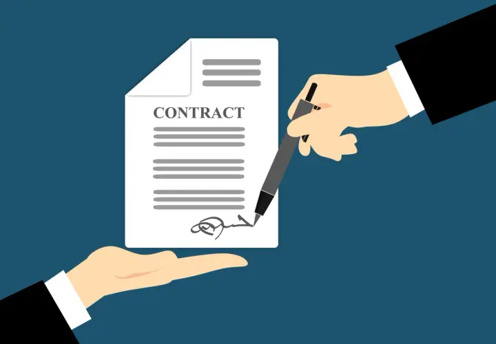 Manos firman un contrato de trabajo. Es obligatorio firmar un contrato de trabajo para formalizar el empleo.