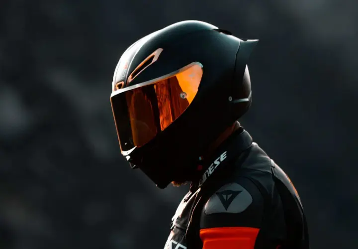Motociclista con casco integral deportivo, uno de los tipos de cascos de moto, con visor naranja reflectante.