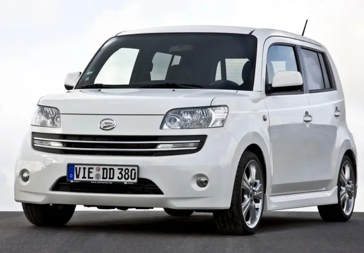 Biały Daihatsu Materia z niemieckimi tablicami rejestracyjnymi stoi na ciemnej nawierzchni.