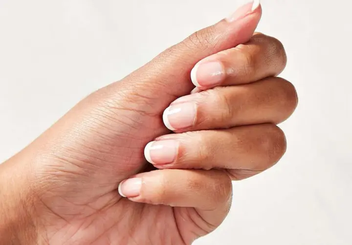 En hand med perfekt fransk manikyr och trind nagellack.