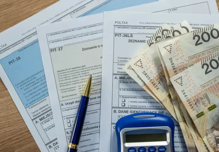 Formularze podatkowe PIT, długopis, kalkulator i banknoty 200 zł. Czas na rozliczenie podatku, zbliża się ikze limit 2026.