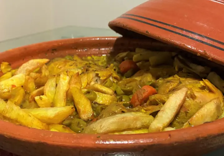 Un plat de tajine poulet olive, avec des pommes de terre dorées et des carottes, prêt à être dégusté.