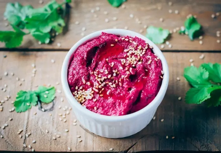 Hummus de remolacha, una de las mejores remolacha recetas, adornado con semillas de sésamo y un chorrito de aceite.