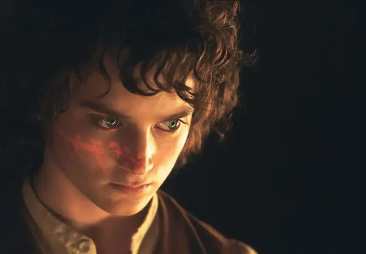 Elijah Wood, kto gra Frodo Bagginsa, z czerwonym znakiem na policzku, w ciemności.