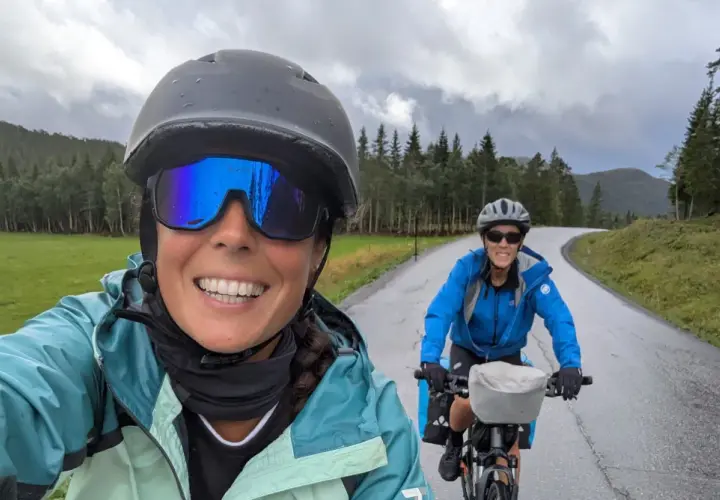 Dos ciclistas disfrutan de una ruta en bicicleta por un paisaje verde y montañoso, ¡una aventura EuroVelo España!