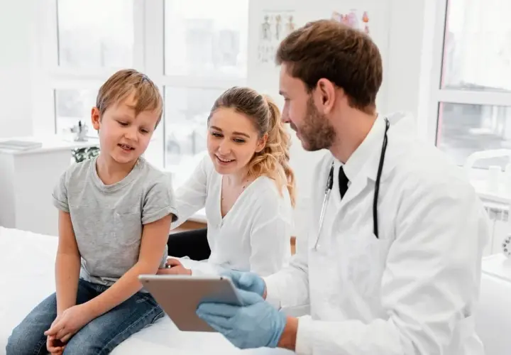 Medico di famiglia: gli orari, le nuove regole. Un dottore mostra un tablet a un bambino e sua madre, spiegando le novità.