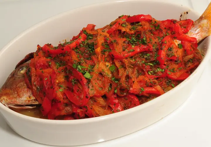 Pescado de roca gallego horneado con pimientos rojos y perejil.