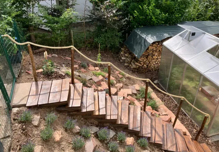 Eine **einfache Gartentreppe selber bauen** ist hier gelungen. Holzstufen führen durch Lavendel und Steine, ein Seilgeländer sorgt für Halt.