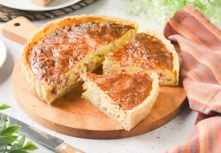 Un delicioso quiche de bacon, recién horneado y cortado en porciones, listo para disfrutar.