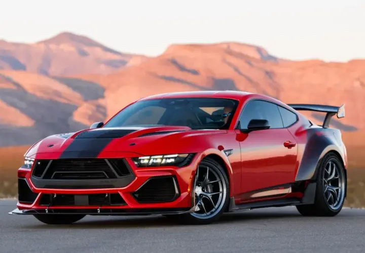 Czerwony mustang shelby z czarnymi pasami i spojlerem na tle pustynnych gór.