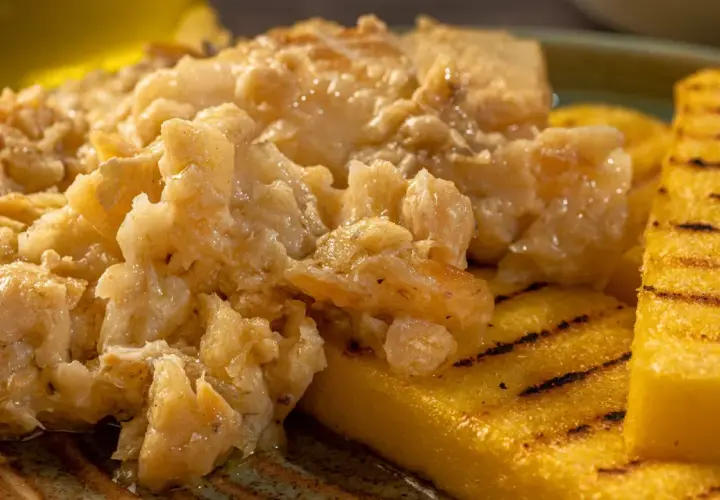 Un saporito baccalà alla vicentina, cremoso e profumato, servito su fette di polenta grigliata.