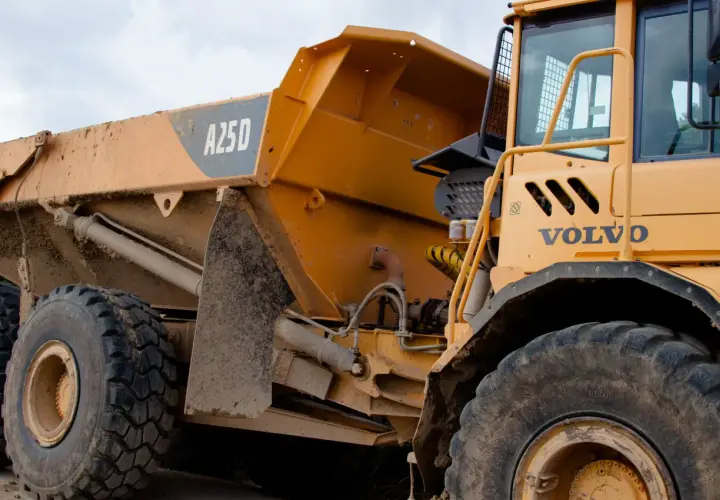 Żółte, masywne **Volvo wozidlo** budowlane z błotem na karoserii i oponach. Widoczna kabina i część skrzyni ładunkowej z oznaczeniem A25D.